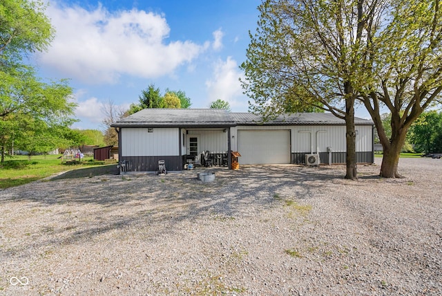 exterior space with an attached garage, ac unit, and gravel driveway