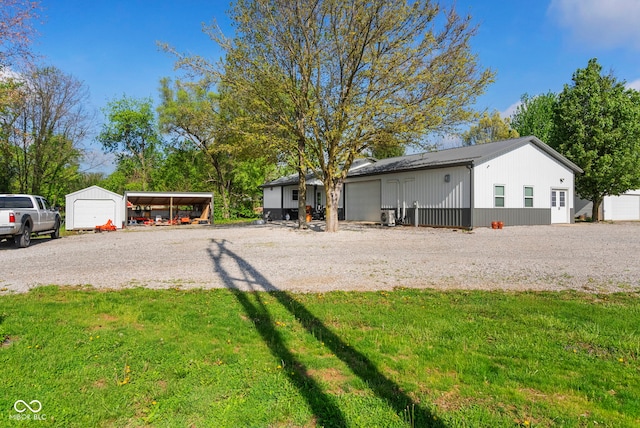 exterior space featuring a garage, an outbuilding, a front yard, a carport, and gravel driveway