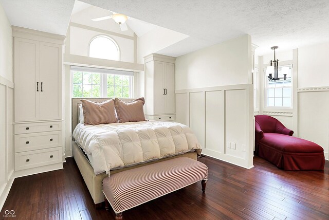 6505 Miramar Ct, Indianapolis, IN 46250 - bedroom featuring a decorative wall, a wainscoted wall, dark wood-style floors, vaulted ceiling, and a textured ceiling