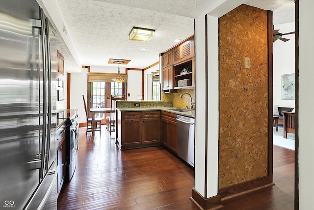 6505 Miramar Ct, Indianapolis, IN 46250 - kitchen featuring stainless steel appliances, a peninsula, a sink, dark wood finished floors, and a textured ceiling