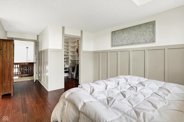 6505 Miramar Ct, Indianapolis, IN 46250 - bedroom with a decorative wall, wood finished floors, a walk in closet, a wainscoted wall, and a closet