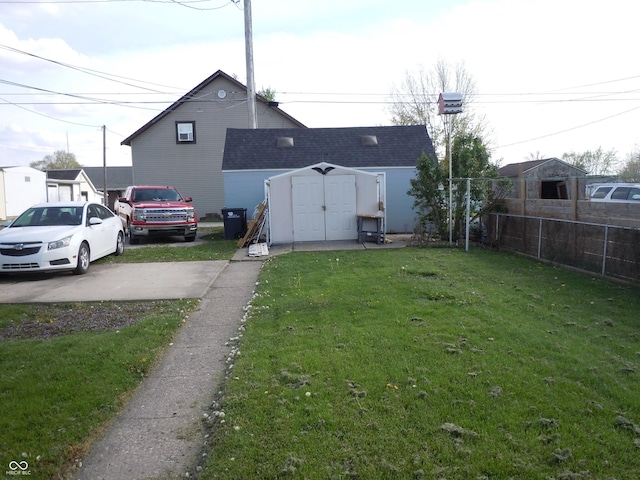 view of yard with an outdoor structure, fence, and a storage unit
