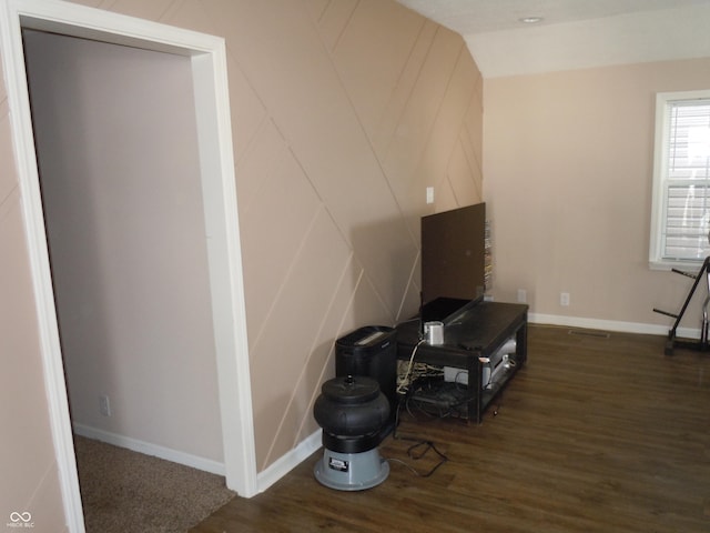 interior details featuring a decorative wall, baseboards, and wood finished floors