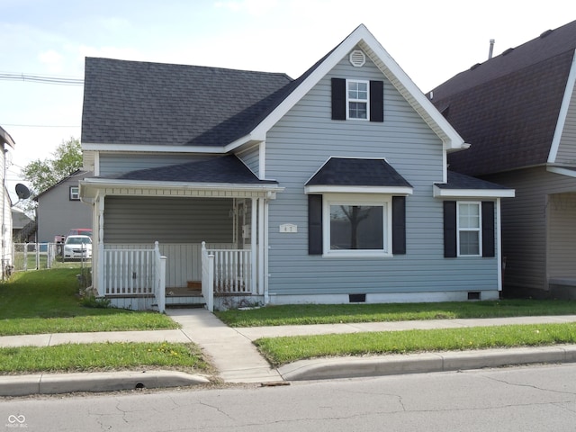 view of front of home with a porch, roof with shingles, fence, and a front yard