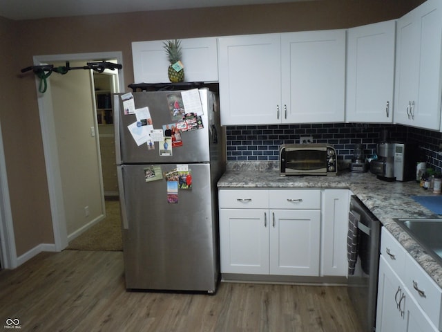 kitchen featuring white cabinetry, appliances with stainless steel finishes, tasteful backsplash, and light wood-style floors