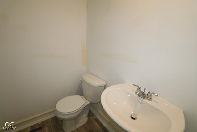 bathroom featuring toilet, a sink, and wood finished floors