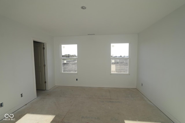 empty room with a wealth of natural light, visible vents, and baseboards
