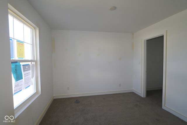 carpeted spare room featuring plenty of natural light and baseboards