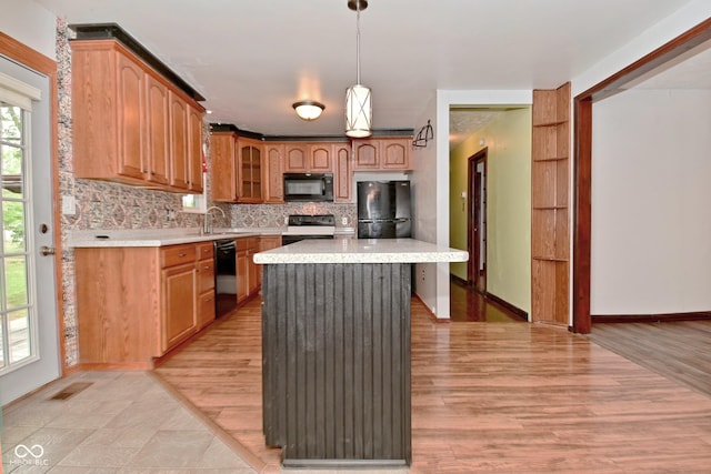 7228 Kimberly Ln, Plainfield, IN 46168 - kitchen with black appliances, light countertops, a kitchen island, decorative backsplash, and a sink
