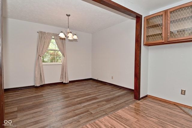 7228 Kimberly Ln, Plainfield, IN 46168 - empty room featuring a chandelier, light wood-style flooring, and baseboards