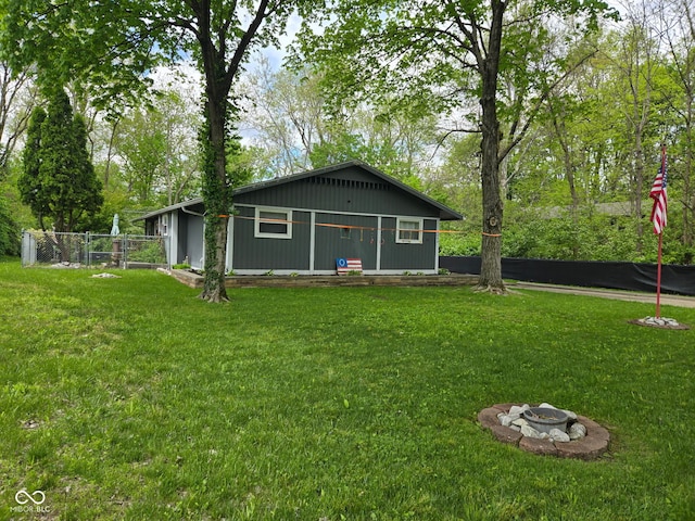 rear view of property with an outdoor fire pit, a yard, and fence