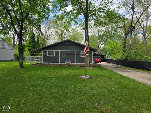 view of front of house featuring concrete driveway, fence, a front yard, and a carport