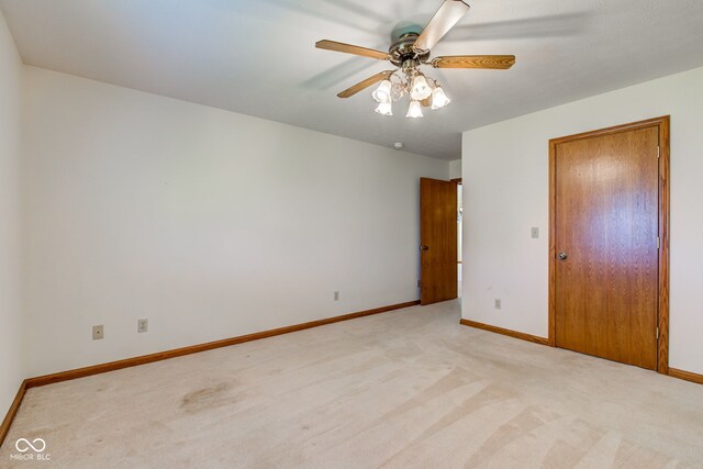 unfurnished bedroom featuring light carpet, baseboards, and a ceiling fan