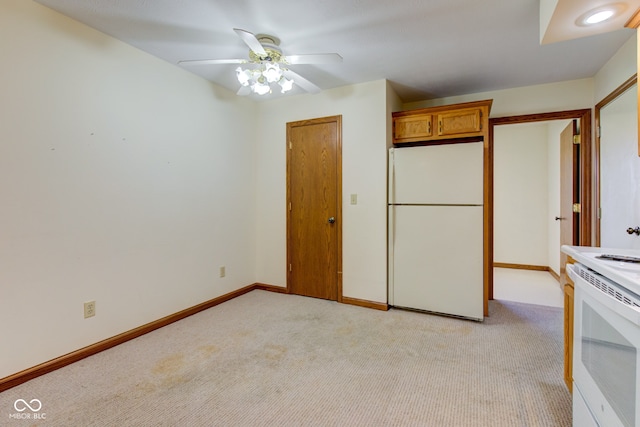 unfurnished bedroom with freestanding refrigerator, light colored carpet, baseboards, and ceiling fan