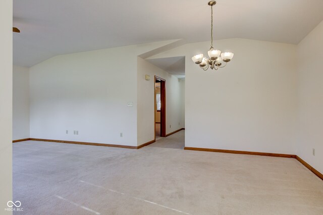spare room with vaulted ceiling, light carpet, baseboards, and a chandelier