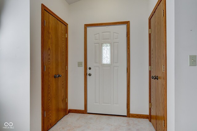 foyer entrance with light carpet and baseboards