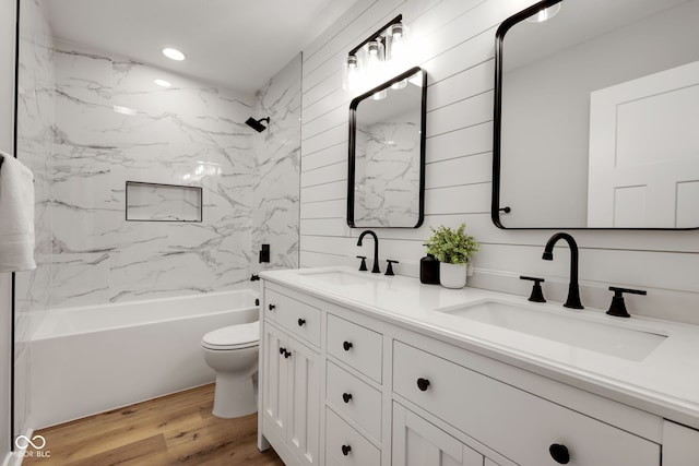 bathroom with double vanity, toilet, wood finished floors, and a sink
