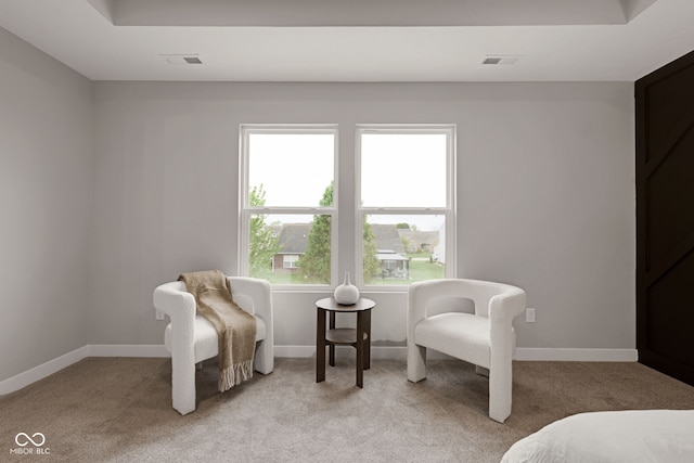 sitting room with light colored carpet, visible vents, and baseboards