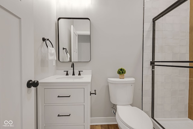 full bath with vanity, toilet, baseboards, and a tile shower