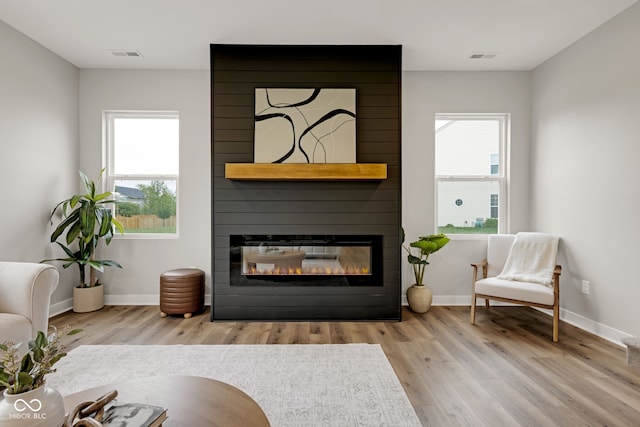 sitting room featuring a wealth of natural light, a fireplace, visible vents, and wood finished floors