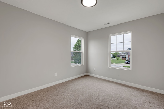 carpeted spare room featuring baseboards and visible vents
