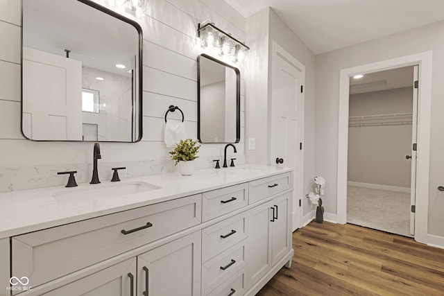 full bathroom featuring baseboards, double vanity, a sink, and wood finished floors