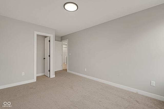 unfurnished bedroom with light carpet, baseboards, and a spacious closet
