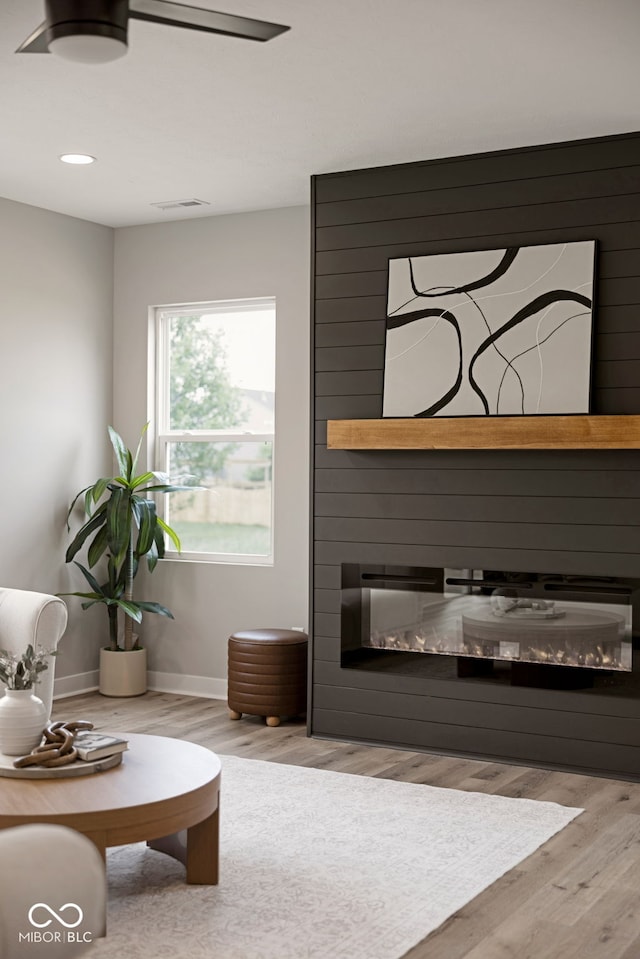 living area featuring recessed lighting, baseboards, visible vents, wood finished floors, and a large fireplace