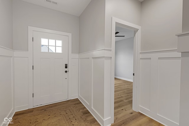 foyer entrance with a wainscoted wall, visible vents, a decorative wall, and light wood-style flooring