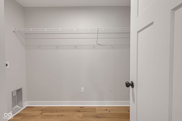 clothes washing area featuring laundry area, wood finished floors, baseboards, and hookup for an electric dryer