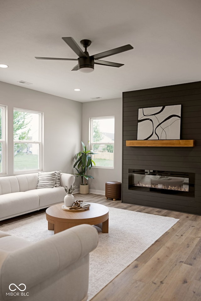 living room with a wealth of natural light, a fireplace, visible vents, and wood finished floors