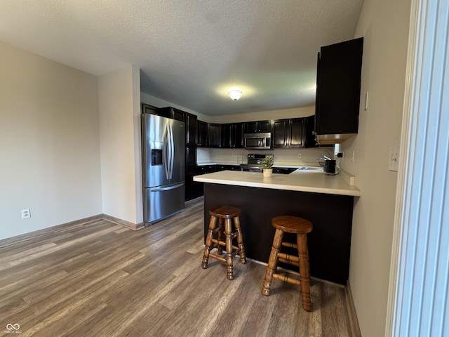 2725 Falcon Ct, Seymour, IN 47274 - kitchen with appliances with stainless steel finishes, wood finished floors, dark cabinetry, light countertops, and a textured ceiling