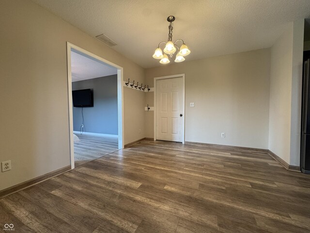 2725 Falcon Ct, Seymour, IN 47274 - unfurnished dining area with a chandelier, wood finished floors, baseboards, and a textured ceiling