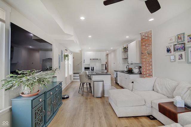 living area featuring light wood-style floors, a ceiling fan, and recessed lighting