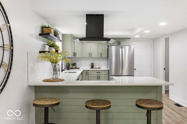 6682 English Dr, Avon, IN 46123 - kitchen featuring freestanding refrigerator, island exhaust hood, a breakfast bar, tasteful backsplash, and a peninsula