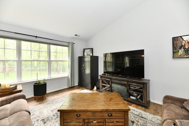 living room with vaulted ceiling, baseboards, visible vents, and wood finished floors