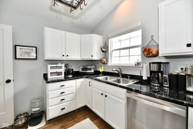 kitchen with a sink, white cabinets, dark wood finished floors, stainless steel dishwasher, and vaulted ceiling