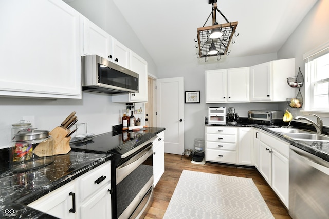 kitchen featuring lofted ceiling, dark wood-style flooring, a sink, white cabinetry, and appliances with stainless steel finishes