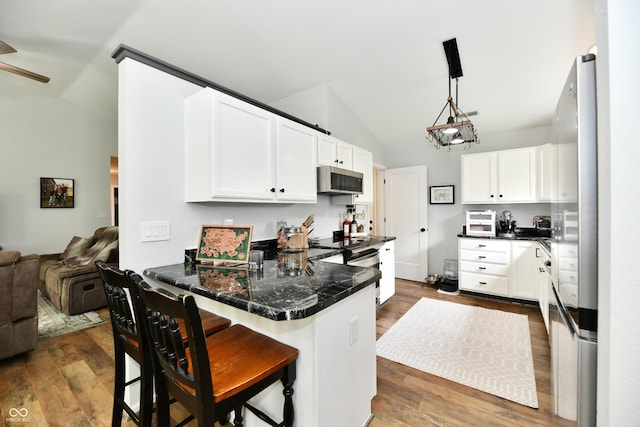 kitchen with a peninsula, appliances with stainless steel finishes, vaulted ceiling, and open floor plan
