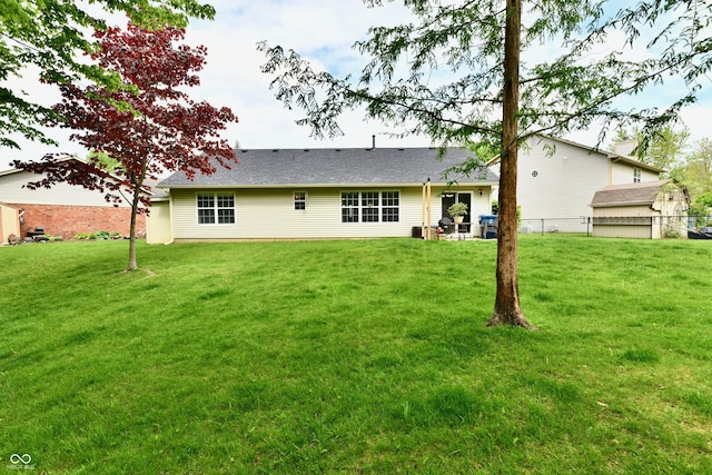 back of property with a lawn and fence