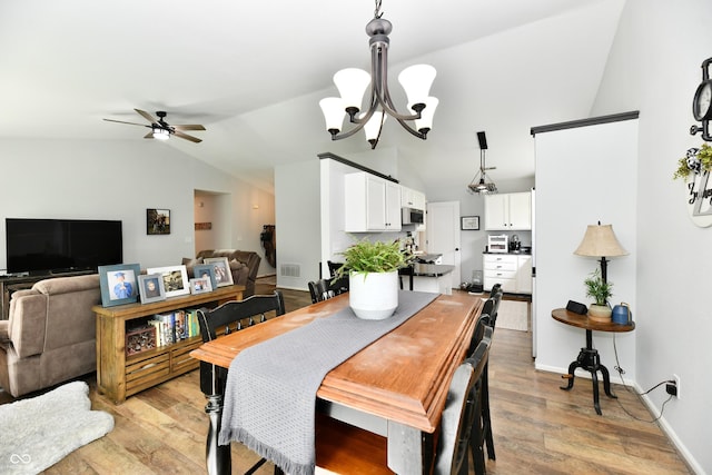 dining area with lofted ceiling, light wood-style flooring, visible vents, and ceiling fan with notable chandelier