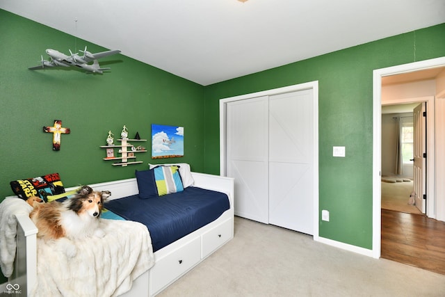 carpeted bedroom with baseboards and a closet