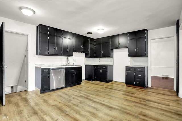 3975 Denwood Dr, Indianapolis, IN 46226 - kitchen with stainless steel dishwasher, dark cabinets, light wood-type flooring, light countertops, and a sink