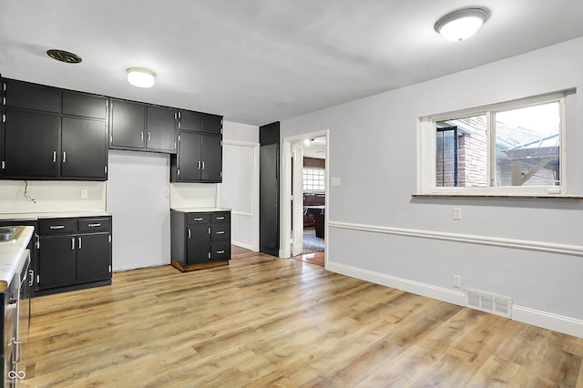 3975 Denwood Dr, Indianapolis, IN 46226 - kitchen featuring dark cabinetry, light countertops, light wood-style floors, and baseboards
