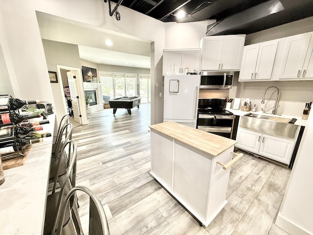 14035 Stone Key Way, Fishers, IN 46037 - kitchen featuring range with electric stovetop, stainless steel microwave, wood counters, white cabinetry, and light wood-type flooring