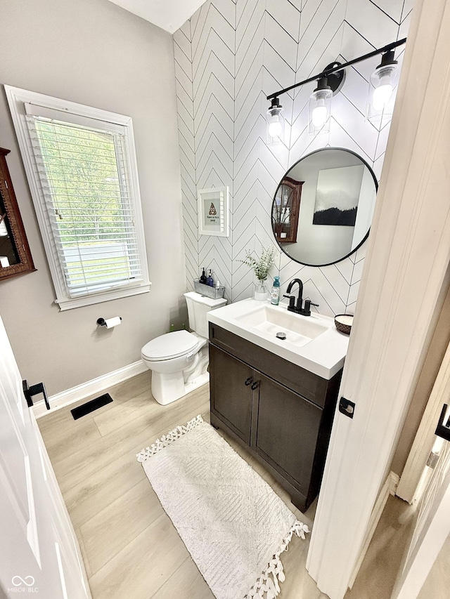 14035 Stone Key Way, Fishers, IN 46037 - half bathroom with toilet, an accent wall, baseboards, vanity, and wood finished floors