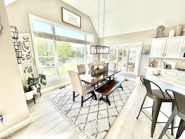 14035 Stone Key Way, Fishers, IN 46037 - dining area with baseboards, light wood finished floors, a chandelier, and high vaulted ceiling