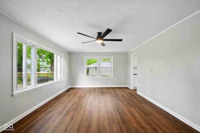 empty room featuring crown molding, dark wood-style flooring, baseboards, and a ceiling fan