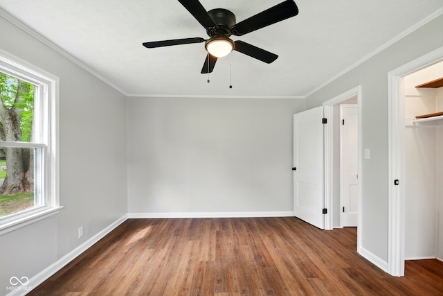 unfurnished bedroom featuring wood finished floors, baseboards, ornamental molding, ceiling fan, and a closet