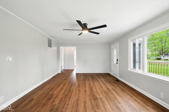 unfurnished room with wood finished floors, a ceiling fan, ornamental molding, and baseboards